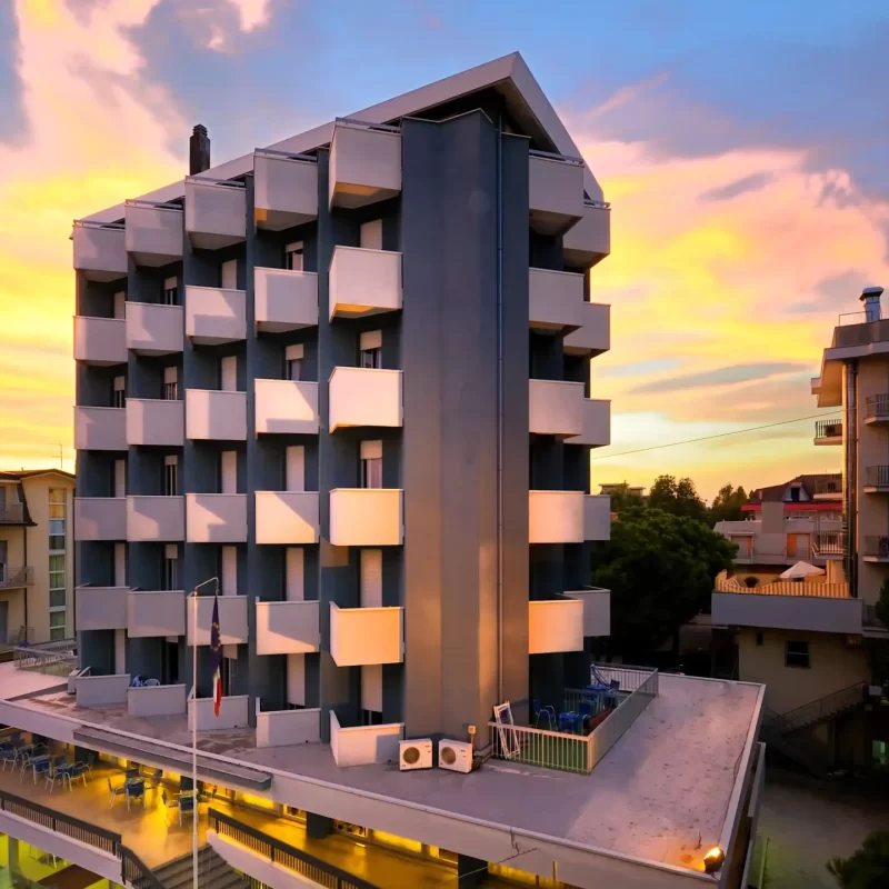 Mehrstöckiges, modernes Gebäude bei Sonnenuntergang mit buntem Himmel.